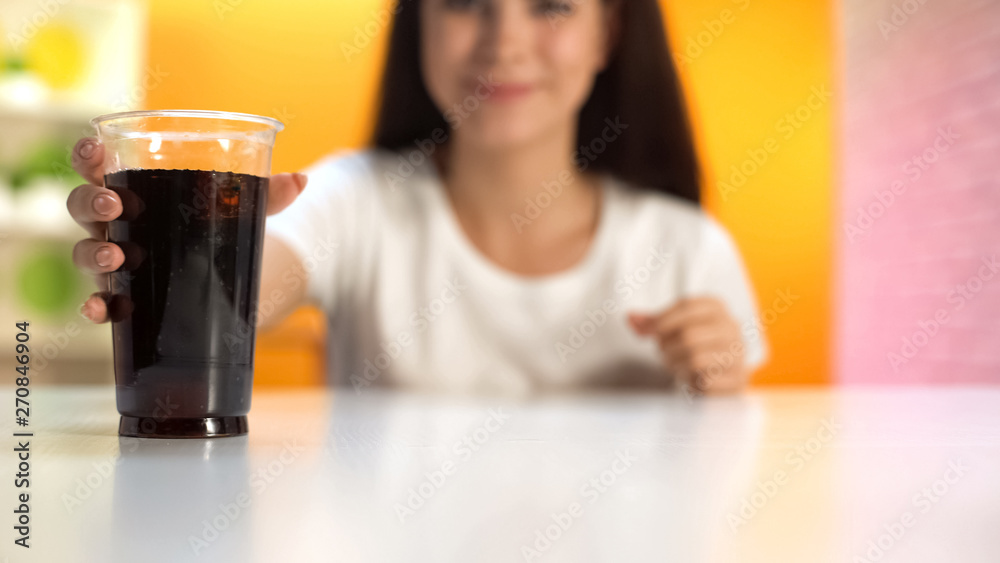 Thirsty woman taking soft drink with ice, plastic glass standing on table, sugar