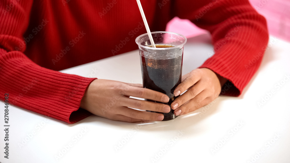 Female customer tasting soft drink from plastic glass through straw, refreshment Female customer tasting soft drink from plastic glass through straw, refreshment