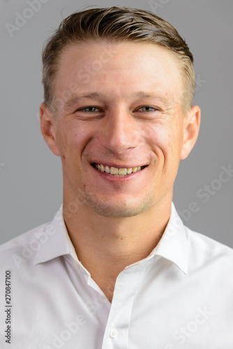 Portrait shot of young happy Caucasian man isolated against gray