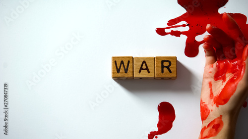 War word made of wooden cubes, bleeding hand on table, political conflict photo