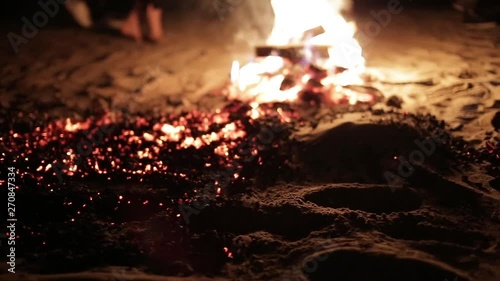 Man with bare feet resolutely walks over hot coals, many participants in the ritual walk around