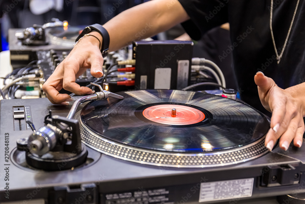 The hands of the DJ spin a record. Close up. Blurred background The hands of the DJ spin a record. Close up. Blurred background