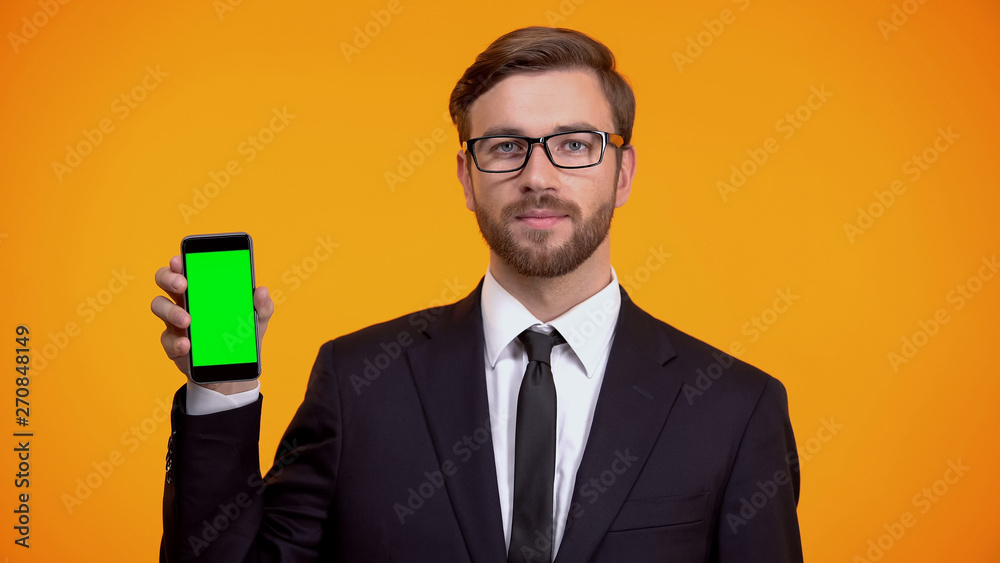Serious man in suit holding green screen smartphone, online schedule app Serious man in suit holding green screen smartphone, online schedule app