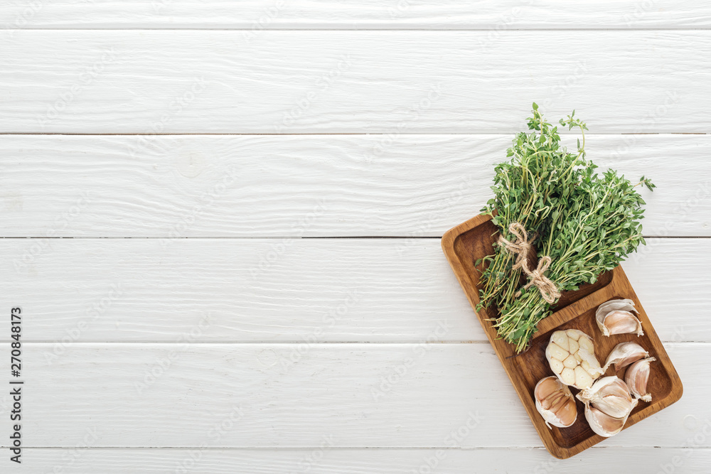 top view of fresh green thyme and garlic cloves on white wooden table top view of fresh green thyme and garlic cloves on white wooden table