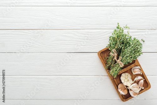 top view of fresh green thyme and garlic cloves on white wooden table