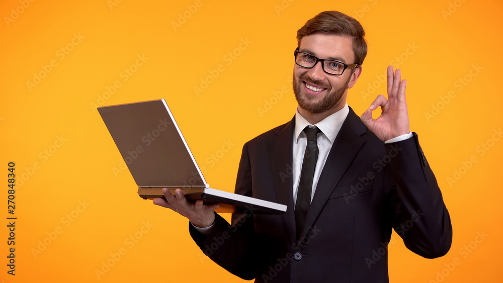 Smiling man reading e-mail and showing ok sign, winking at camera, promotion Smiling man reading e-mail and showing ok sign, winking at camera, promotion