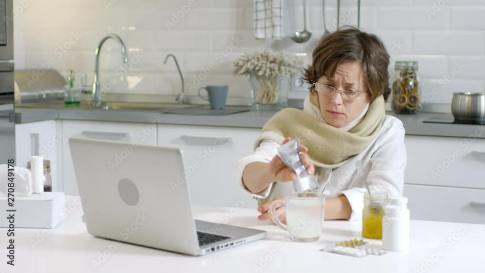 Sequence of videos with sick Caucasian woman sitting at kitchen table at PC, pouring medical powder out of pack into water cup and discussing her health state with female doctor by video call Sequence of videos with sick Caucasian woman sitting at kitchen table at PC, pouring medical powder out of pack into water cup and discussing her health state with female doctor by video call