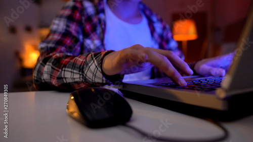 Hand of nervous boy pressing key, playing video games on laptop, addiction