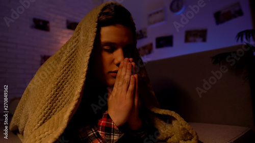 Canvas Print Religious teenager praying covered with blanket, belief in god, sectarianism