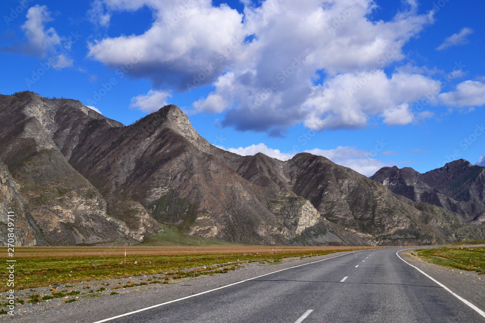 Naklejka premium Empty road to the mountains on a sunny day.