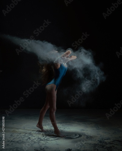Graceful woman dancing in dust cloud profile view