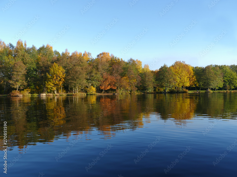 Beautiful autumn landscape of colorful trees reflected in the blue water lake