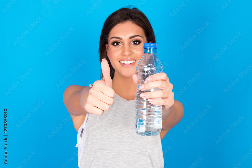 Beautiful teen girl holding bottle of water, smiling and drinking fresh  water Stock Photo