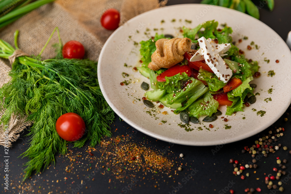 Greek salad of fresh cucumber, tomato, sweet pepper, lettuce, red onion, feta cheese and olives with olive oil. Healthy food, top view. Black background . Slow-mo.