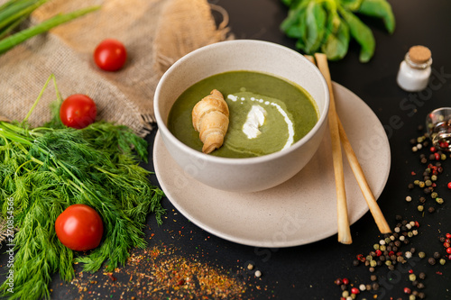 Green cream soup of spinach and broccoli. with the addition of parmesan and blue cheese with croissant. a black background. conception healthy food and diet. Slow-mo.