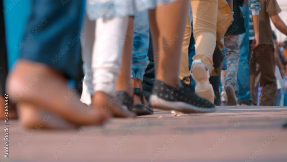 Feet without shoes of people dressed in colorful traditional Indian clothes are walking on historical landmark, India