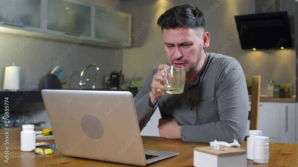 Sequence of videos with ill middle-aged man sitting at kitchen table in front of laptop, drinking hot drink and having online consultation of female physician Sequence of videos with ill middle-aged man sitting at kitchen table in front of laptop, drinking hot drink and having online consultation of female physician