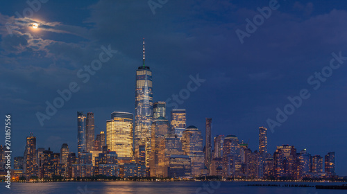 Panoramic view of Financial district with full moon at night from Hudson river