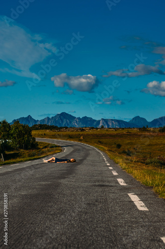 Girl in blue dress laying on the road  in  Straumnes photo