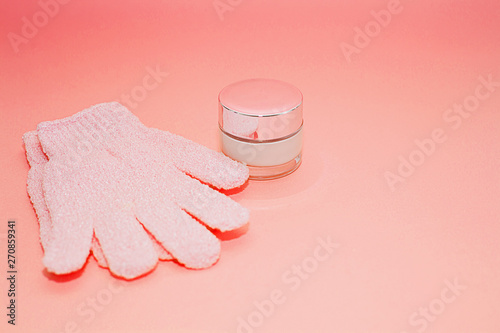 Beauty luxury cosmetic cream container and bath massage gloves on color of the year 2019 - Living Coral background. Background with facial cosmetic products. Package for cream. Beauty and spa concept