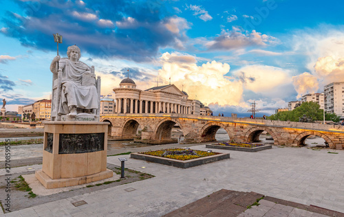 SKOPJE, NORTH MACEDONIA - 25.04.2019: Byzantine Emperor Justinian Statue and Stone Bridge, behind the Archeology Museum at sunset in Skopje photo