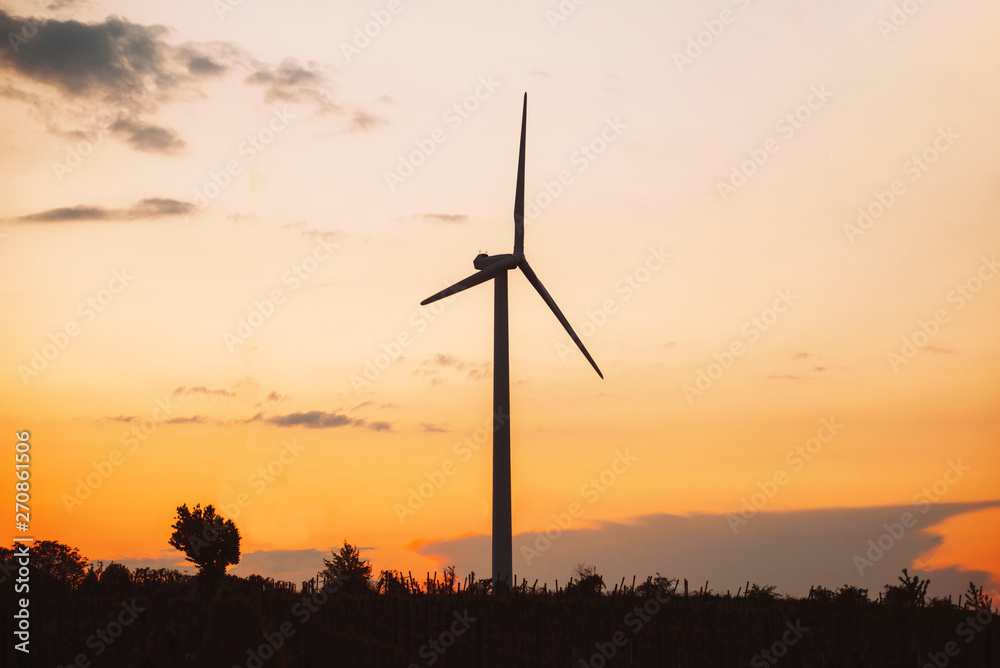 Obraz premium Turbina wiatrowa wytwarzająca zieloną energię podczas zachodu słońca