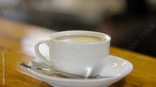 Wallpaper Mural Close-up cinemagraph of steaming hot Americano coffee with milk in white cup on saucer sitting on wooden counter in café, against dark blurred background Torontodigital.ca