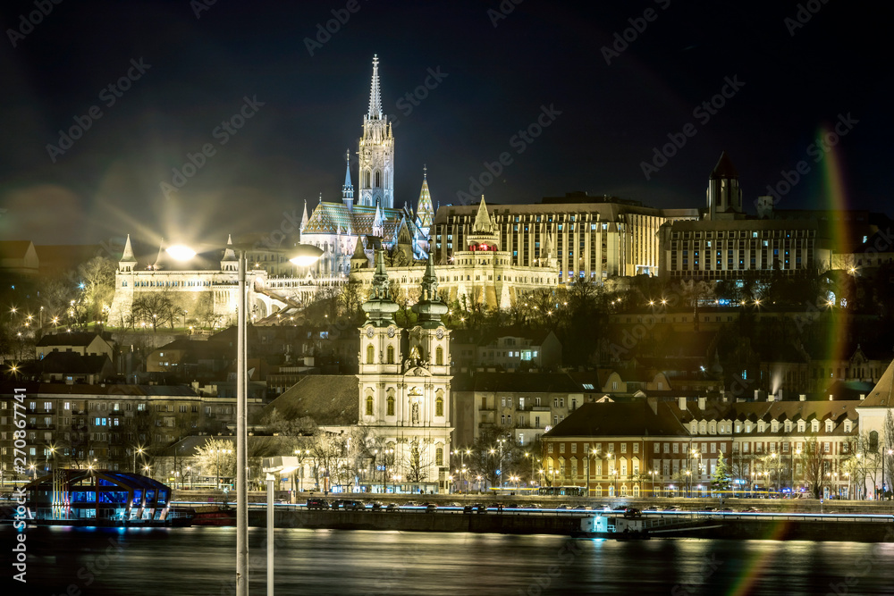 Night view of St. Matthias Church from the east side of Danube with motor ships on it