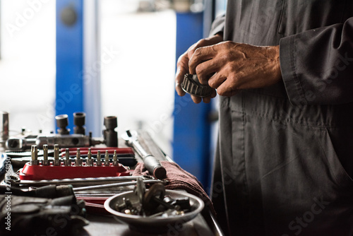 Mechanic hands holding car part next to tools