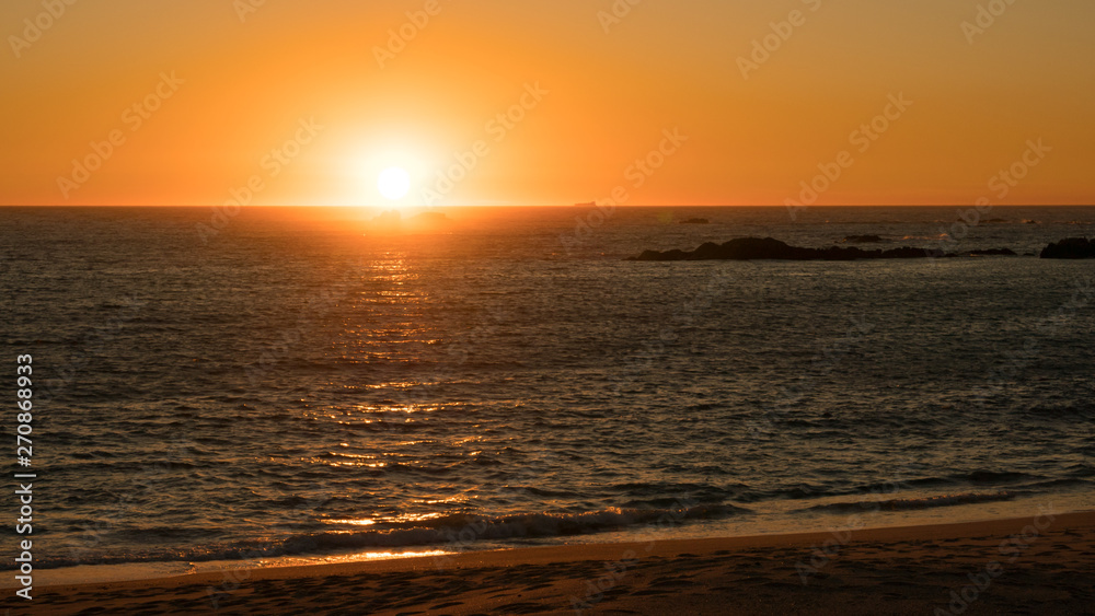 Beautiful sunset on beach in Portugal as sun dips below horizon.