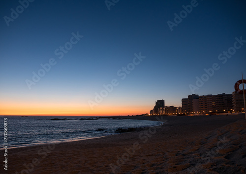 Sunset on the beach in Povoa de Varzim, Portugal with vibrant blue orange gradient sky