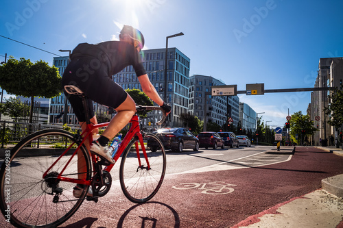 Cyclist ride along a red lane marked with a bicycle symbol, through a business area in Oslo, Norway.