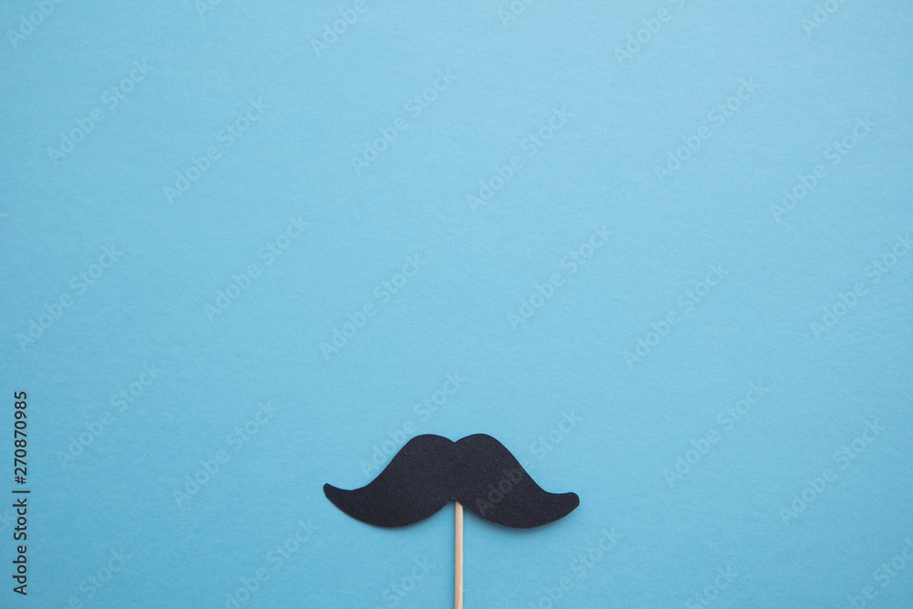 Black paper mustache on a blue background. Father's day or mens health concept