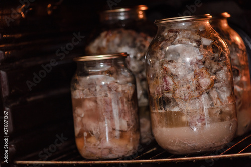 Glass jars with a stewed pork in hot oven. Homemade cooking with a traditional recipe, Ukrainian cuisine