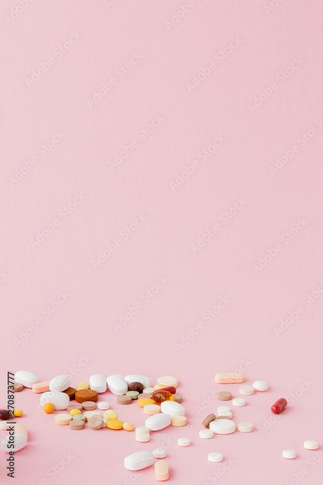 group of capsules and pills in different colors and shape isolated on pink background