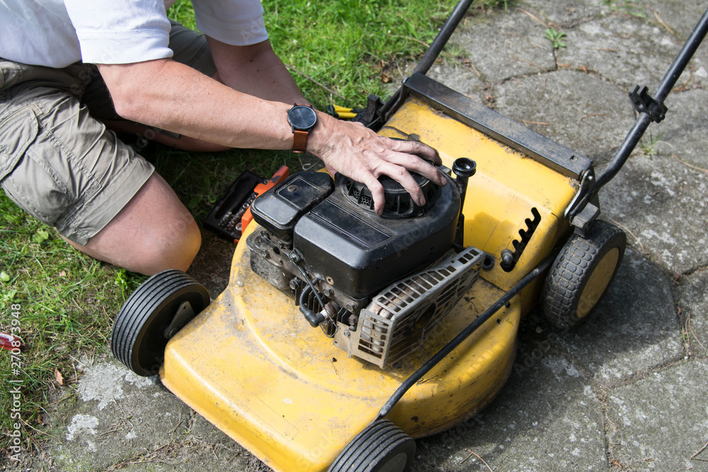 Fototapeta premium Man repairing an old lawn mower