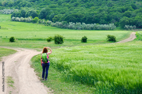 Young woman looking into the distance - Macin mountains, Dobrogea, Romania, at the beginning of the route called Cozluk. Layers of rye and wheat fields with a forest treeline in the distance.