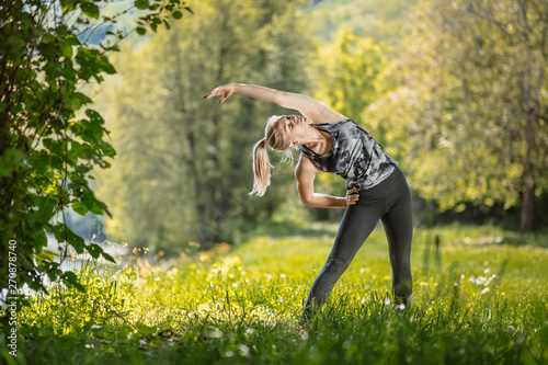 Young, blonde fit woman doing her training in the nature by the river.