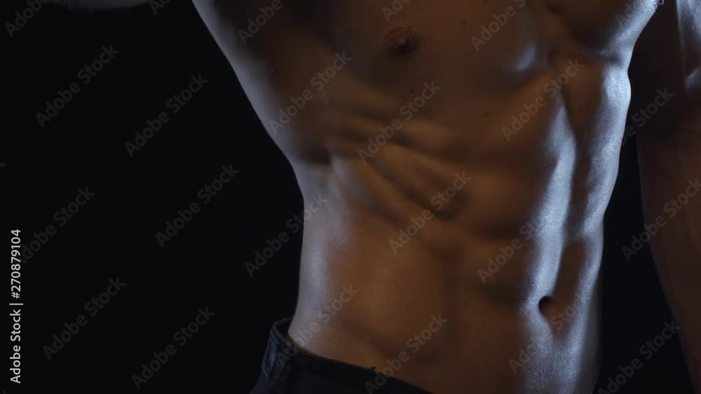 Young fit guy posing, showing abdominal side muscles, slow motion Young fit guy posing, showing abdominal side muscles, slow motion