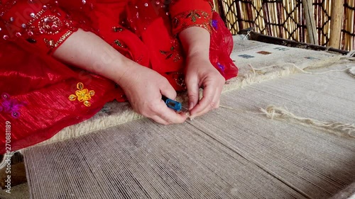 Qashqai Woman in Red Weaves Carpet Closeup. photo