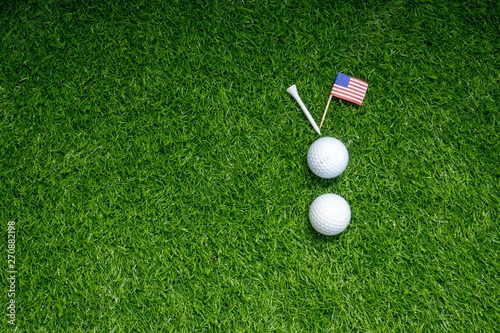 Golf ball with flag of America on green grass.