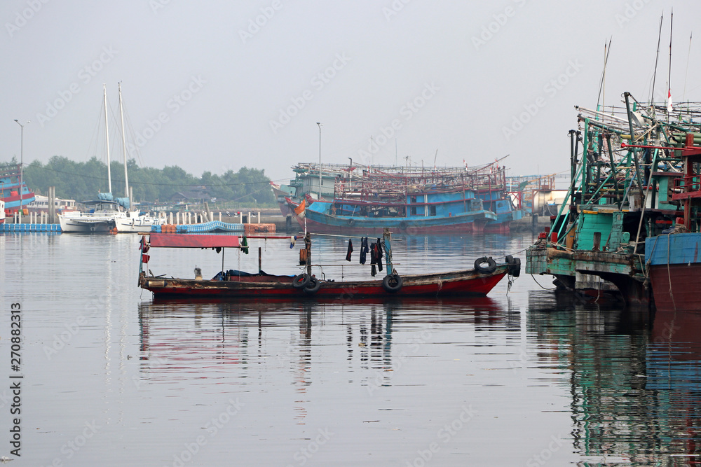 Small boat tied to the fishing boat with fishings boat and other boats.