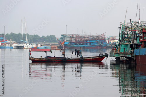 Small boat tied to the fishing boat with fishings boat and other boats.