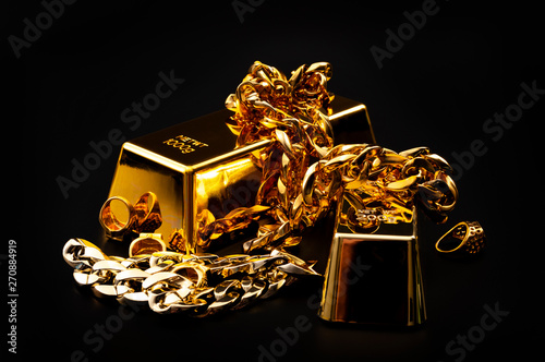 Jewelry buyer, pawn shop and buy and sell precious metals concept theme with a pile of golden rings, necklace bracelet and gold bullion isolated on black background photo