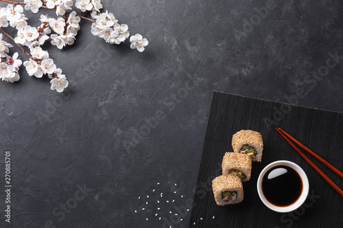 Set of sushi and maki rolls with branch of white flowers on stone table photo