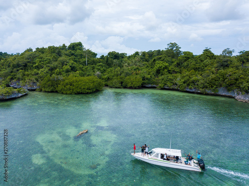 Aerial photography view of Wakatobi (Wangi-Wangi, Kaledupa, Tomia & Binongko) islands with a white boat, Southeast Sulawesi, Indonesia