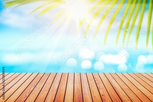 Blur tropical beach with bokeh sun light wave and palm tree on empty old wood table abstract background.