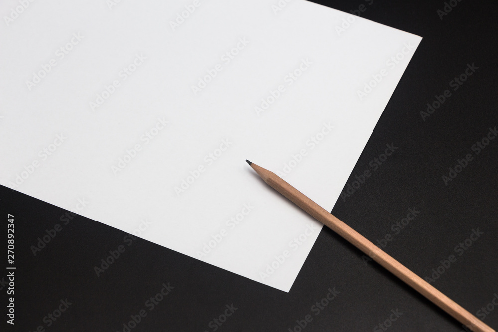 A brown pencil and a piece of white paper are placed on the black class desktop A brown pencil and a piece of white paper are placed on the black class desktop