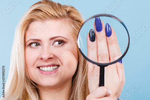 Woman looking at nails through magnifying glass