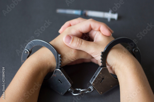 hands in handcuffs with a syringe